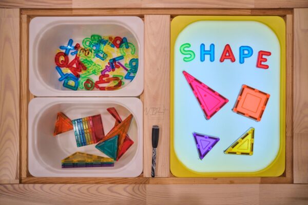 light table insert used on an IKEA Flisat sensory table, working as a functional light table cheap alternatives. Paired with magnetic tiles and transparent colored letters